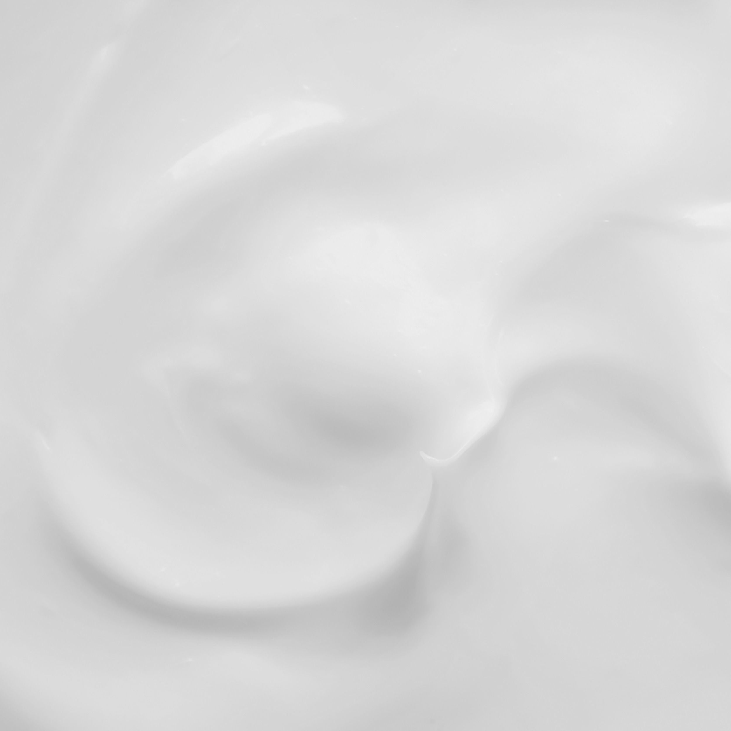 Gros plan d'une lotion corporelle blanche et crémeuse. La texture est lisse et onctueuse.
