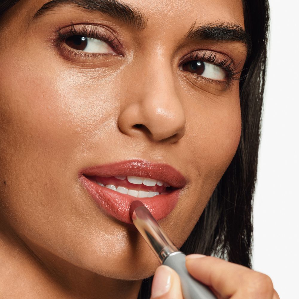 Vrouw brengt lippenstift aan. De lippenstift is roodbruin.