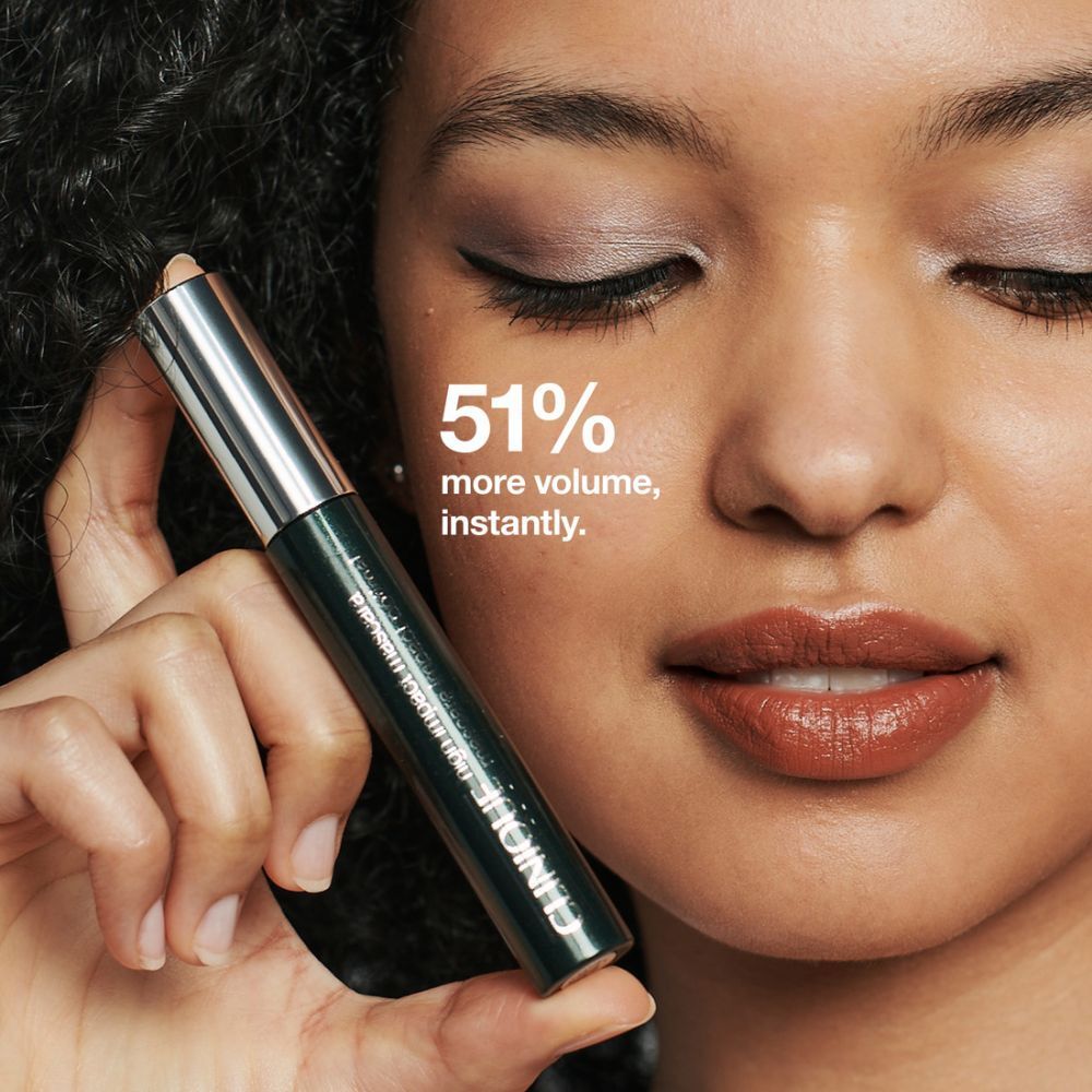 Femme tenant du mascara. Texte : 51 % de volume en plus, instantanément. Tube de mascara en main.