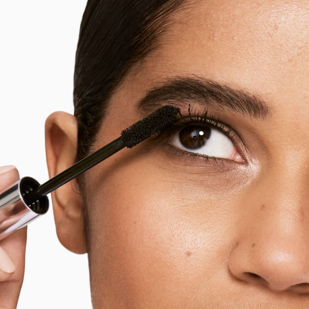 Femme appliquant du mascara. Brosse noire appliquée sur les cils.