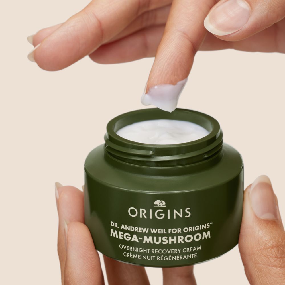 Handen houden groene pot vast, vinger met crème. Tekst Origins, Mega-Mushroom.