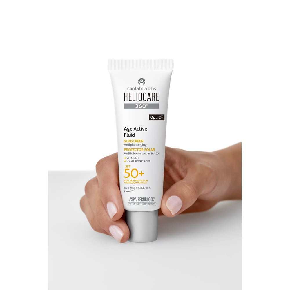 Hand houdt witte tube vast. Opschrift: Heliocare 360° Age Active Fluid SPF50+. Merk: Cantabria Labs.