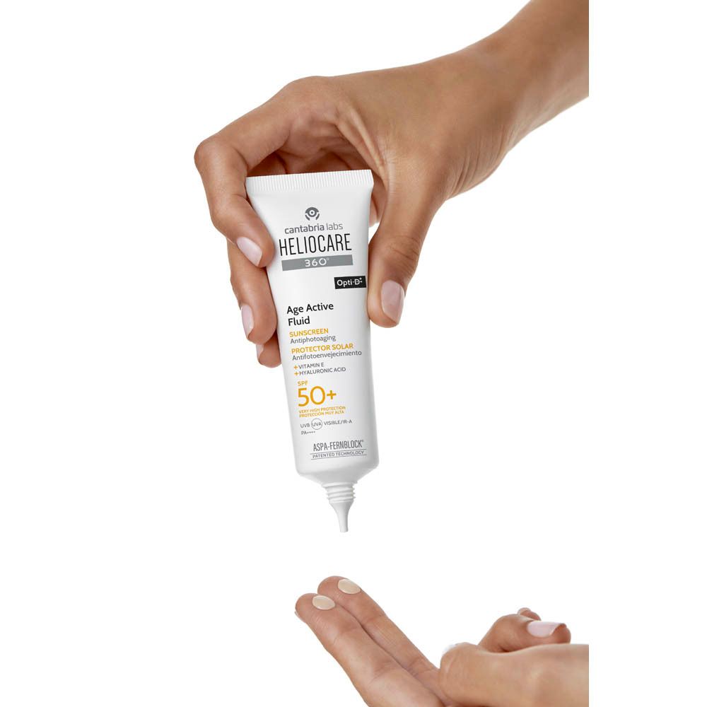 Hand houdt witte tube vast. Opschrift: Heliocare 360° Age Active Fluid SPF50+. Merk: Cantabria Labs.