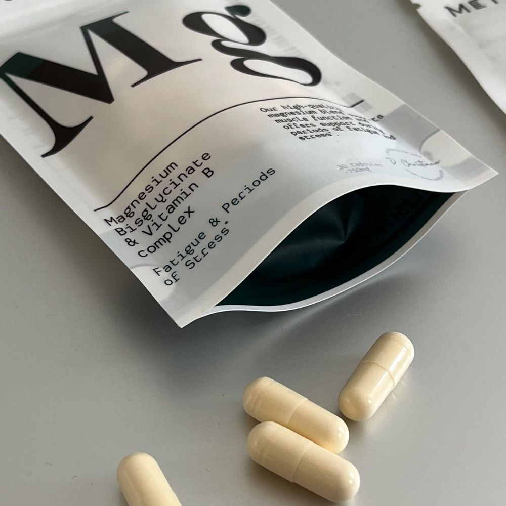 Open verpakking met capsules. Enkele capsules ernaast. Tekst: Magnesium Bisglycinaat & Vitamine B complex. Fatigue & Stress.