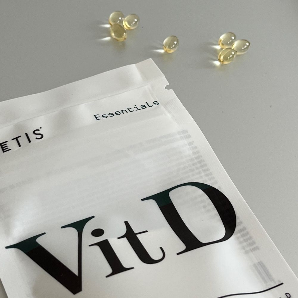 Capsules en verpakking van Metis Essentials Vit D. Enkele capsules naast de verpakking.