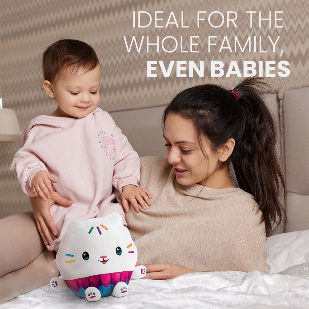 Een vrouw houdt een baby vast, beiden kijken naar een zachte, witte katten-warmwaterkruik met gekleurde strepen.