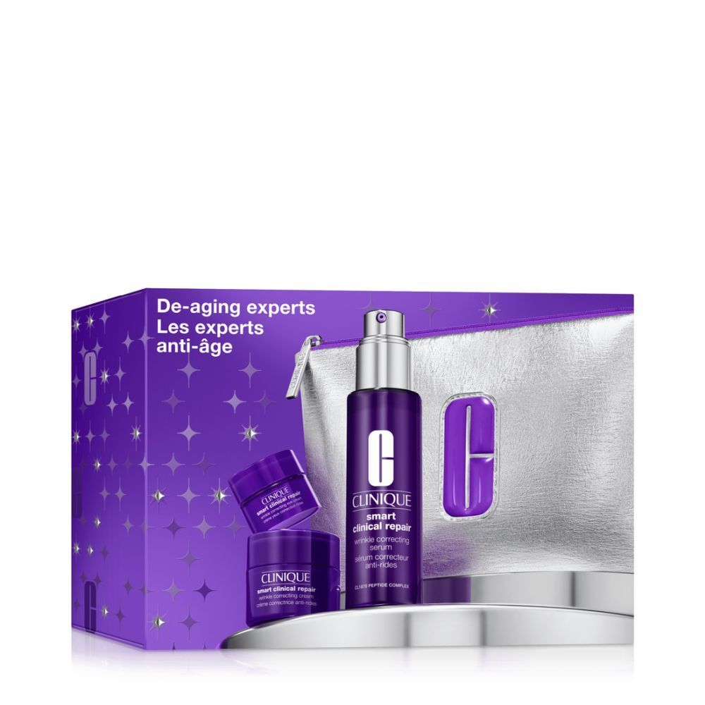 Coffret cosmétique dans une boîte violette avec trousse argentée et produits. Texte: De-aging experts, Clinique.
