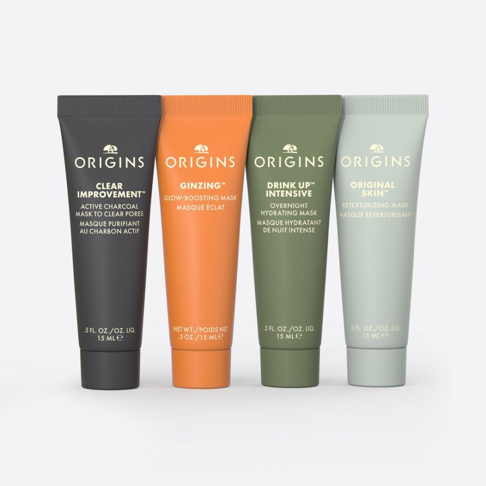 Quatre tubes de masques faciaux. Noir, orange, vert et vert clair. Inscriptions : Origins, noms de produits et ingrédients.