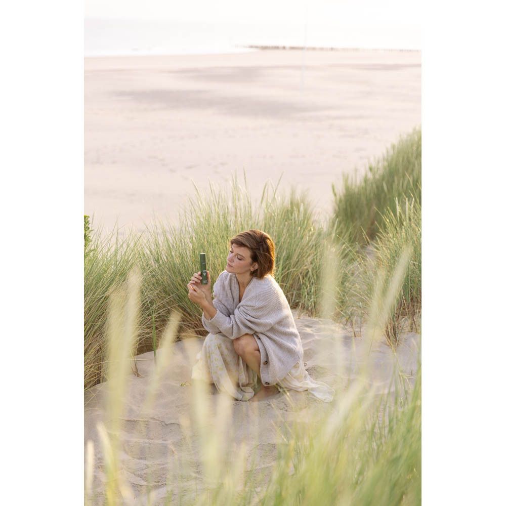 Flacon vert sur un rocher dans l'eau. Texte: CÎME, Lynn. Crème jour & nuit.