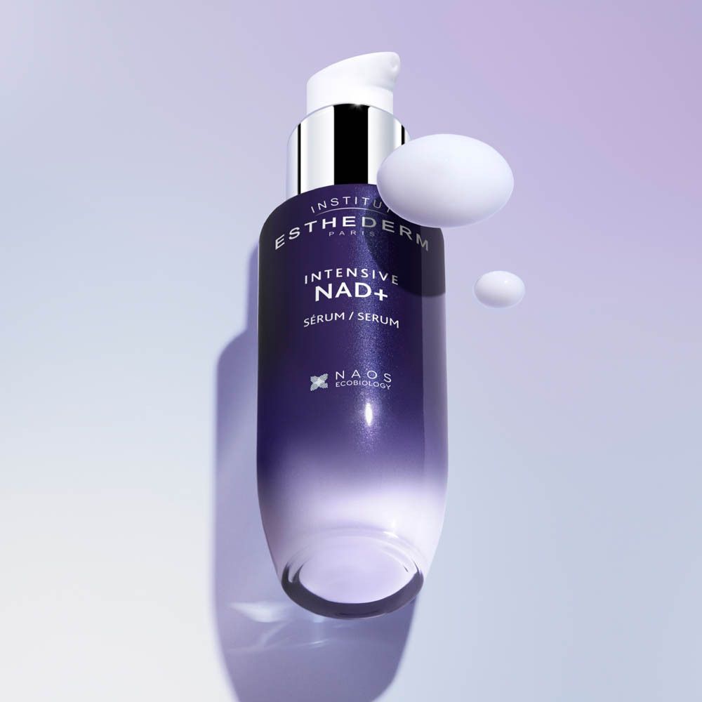 Achterkant van een donkere glazen fles Institut Esthederm Intensive NAD+ serum met productinformatie.