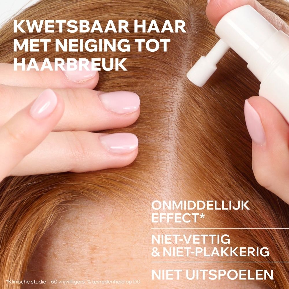Een hand brengt een witte spray aan op de hoofdhuid voor de behandeling van breekbaar haar.