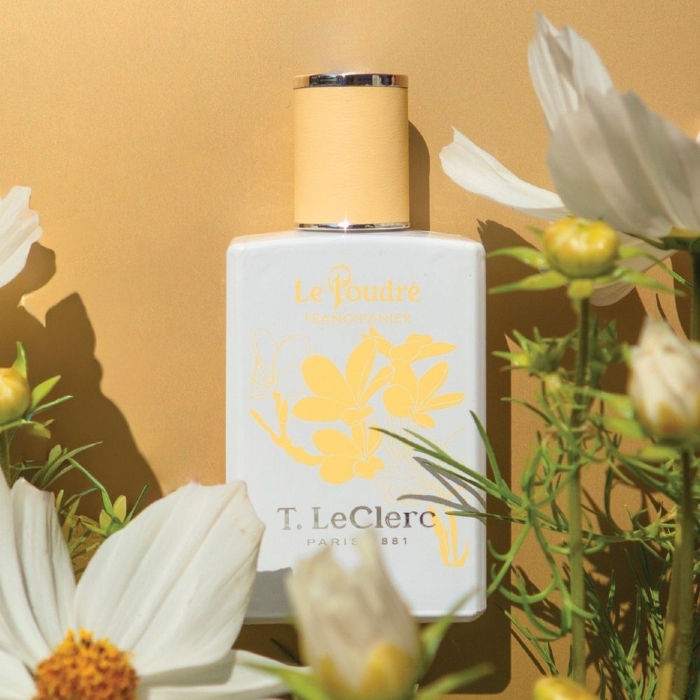 T. LeClerc Eau de Parfum Le Poudré Frangipanier fles tussen bloemen.