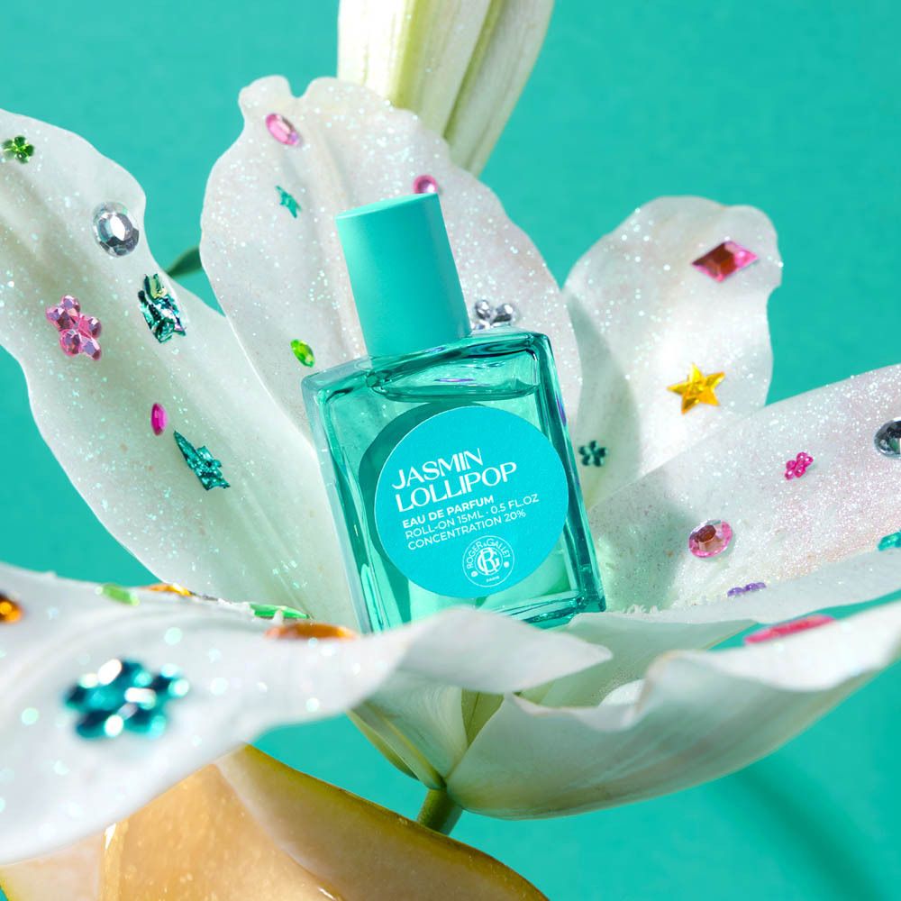 Achterkant van de Jasmin Lollipop Eau de Parfum Roll-on. Tekst op turquoise achtergrond. Witte bloem.
