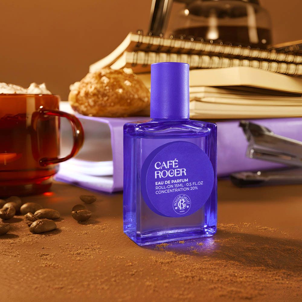 Roll-on parfum op een tafel met koffie, notitieboekjes en paperclips.