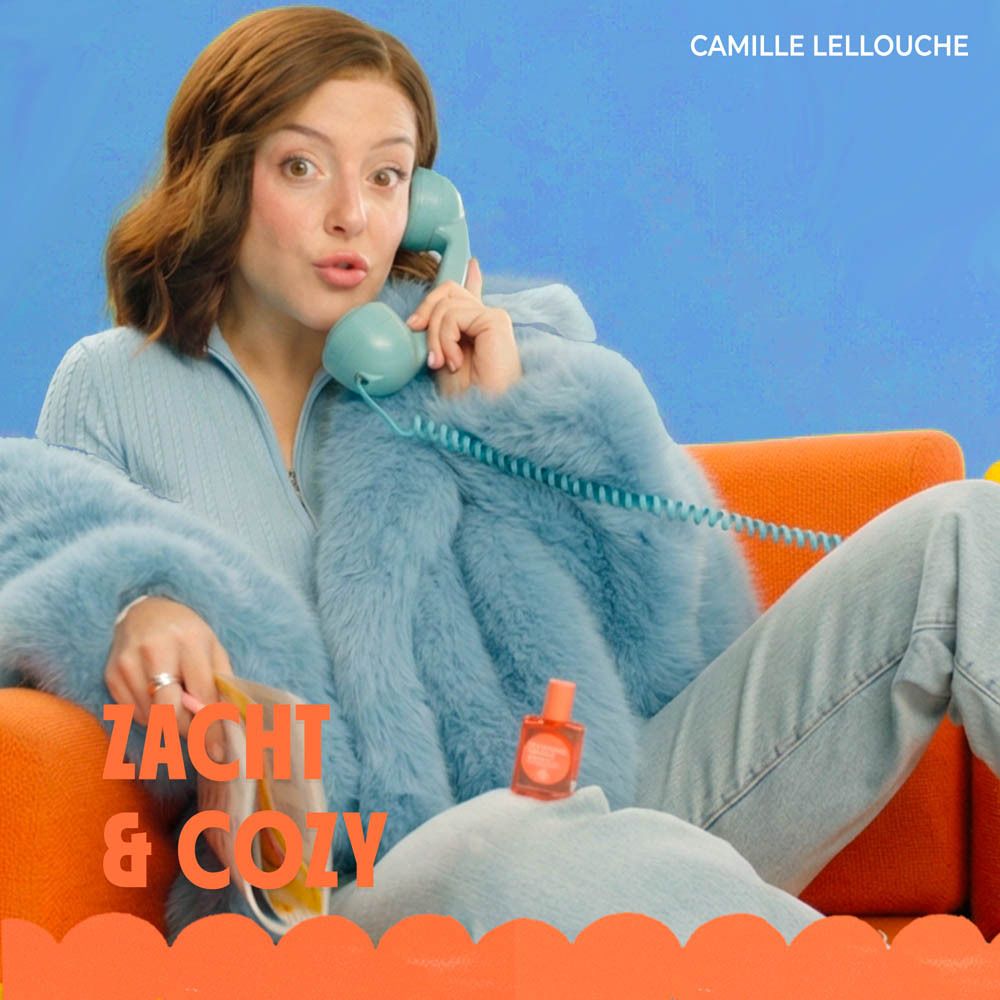 Vrouw aan de telefoon met fles. Tekst: Zacht & Cozy. Fles: Mandarine Doudou. Oranje.