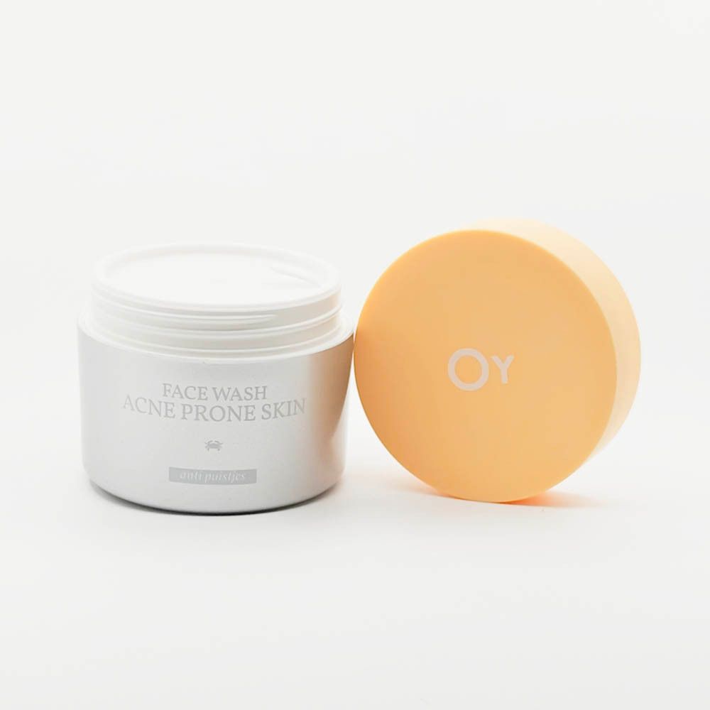 Witte pot met gele deksel. Deksel ernaast. Opschrift: Face Wash Acne Prone Skin. Oy logo.