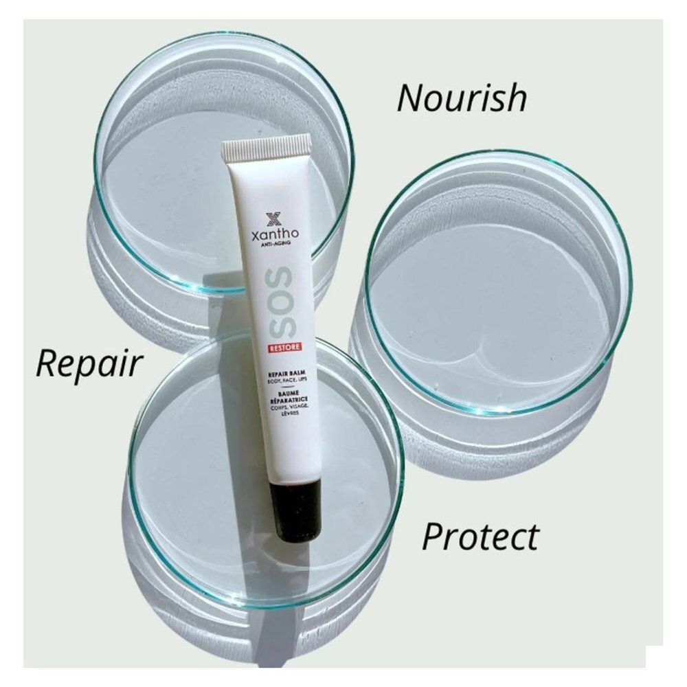 Witte tube "SOS Restore Repair Balm" op drie petrischalen. Opschriften: Repair, Nourish, Protect. Voor lippen, gezicht, lichaam.