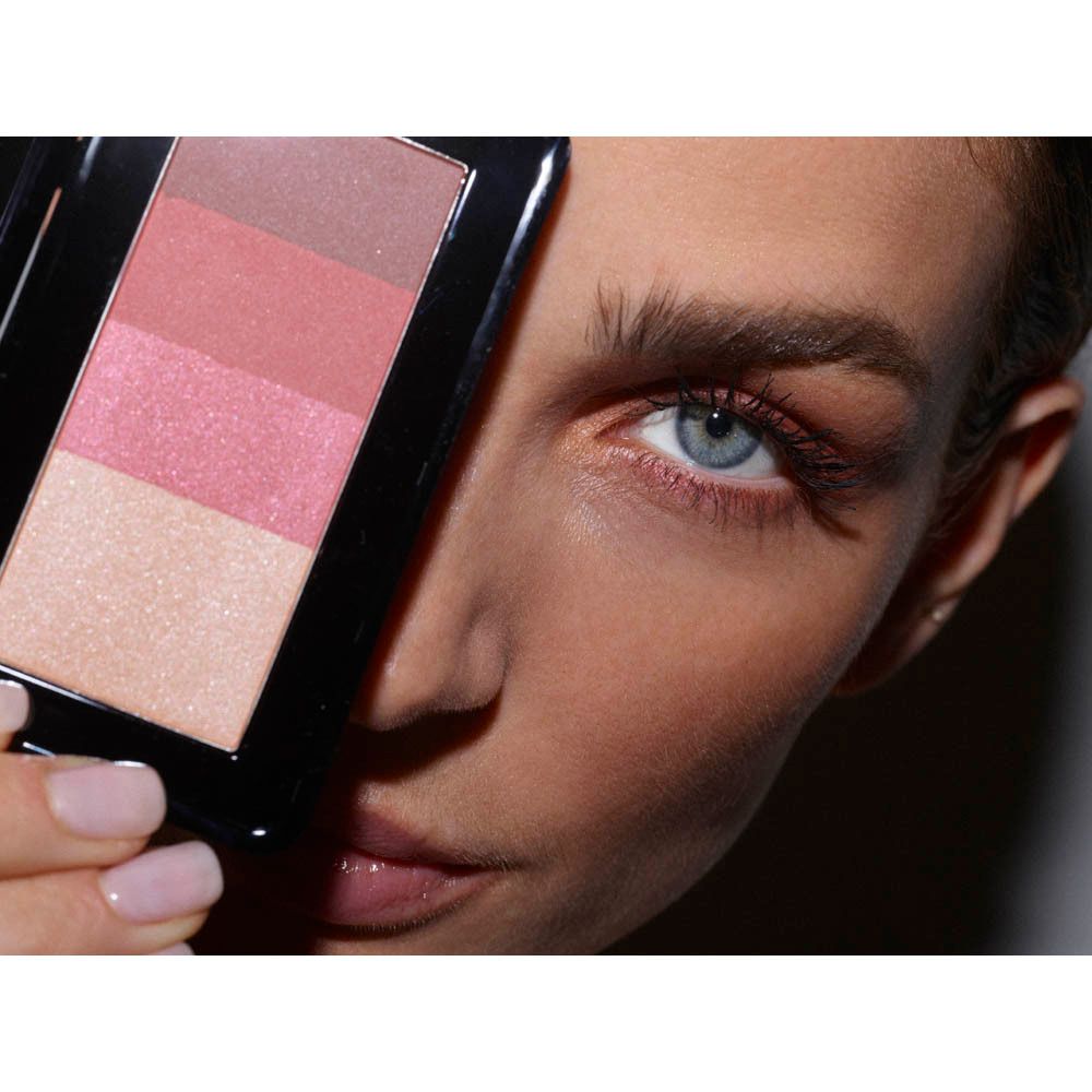 Femme tenant la palette d'ombres à paupières 03 Les Bordeaux devant son visage, teintes visibles.