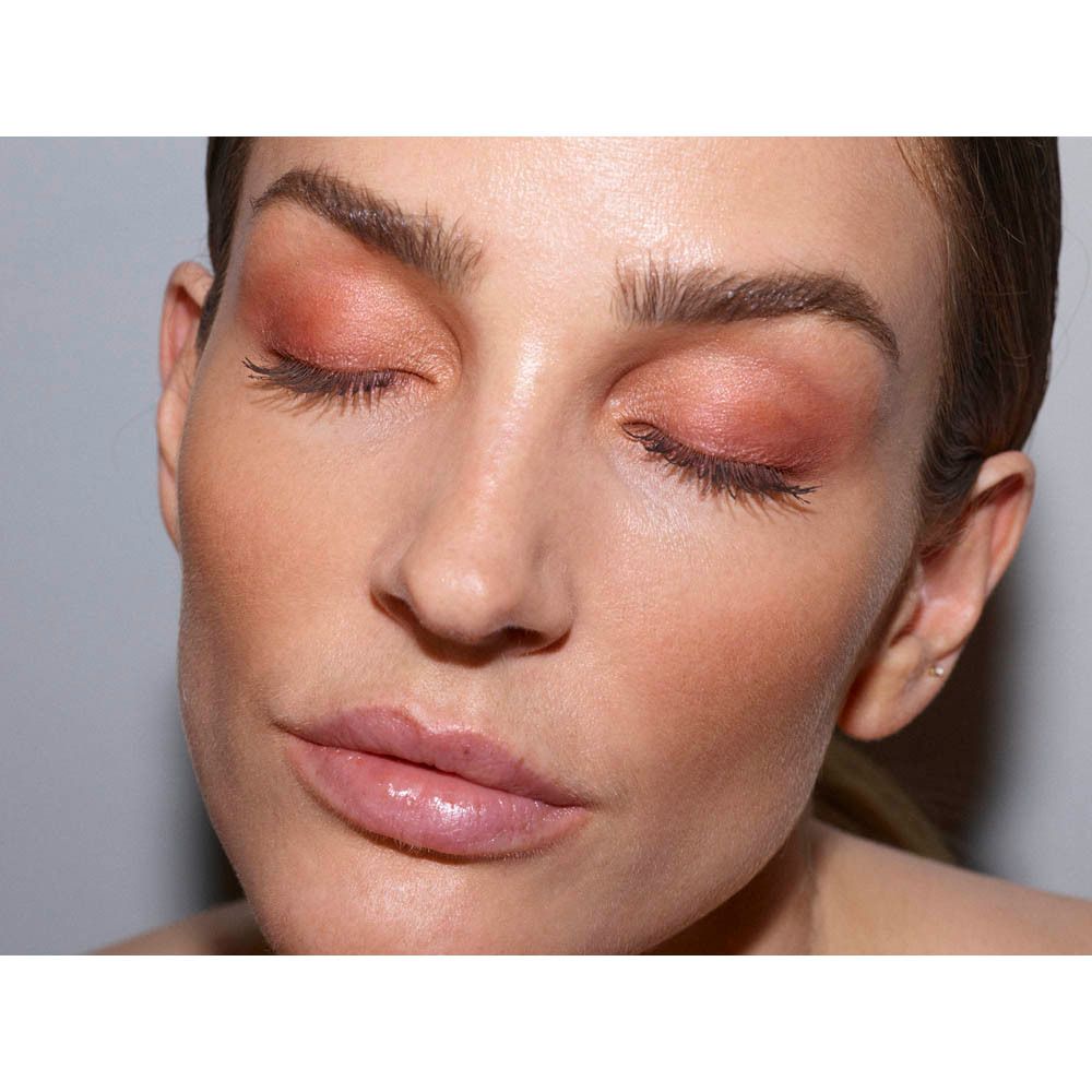 Femme aux yeux fermés, maquillée avec des fards à paupières aux tons rosés chauds.