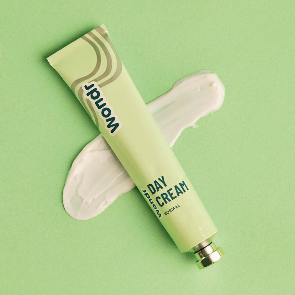 Crème à côté du tube. Texte : Day Cream, Normal. Sur fond vert.