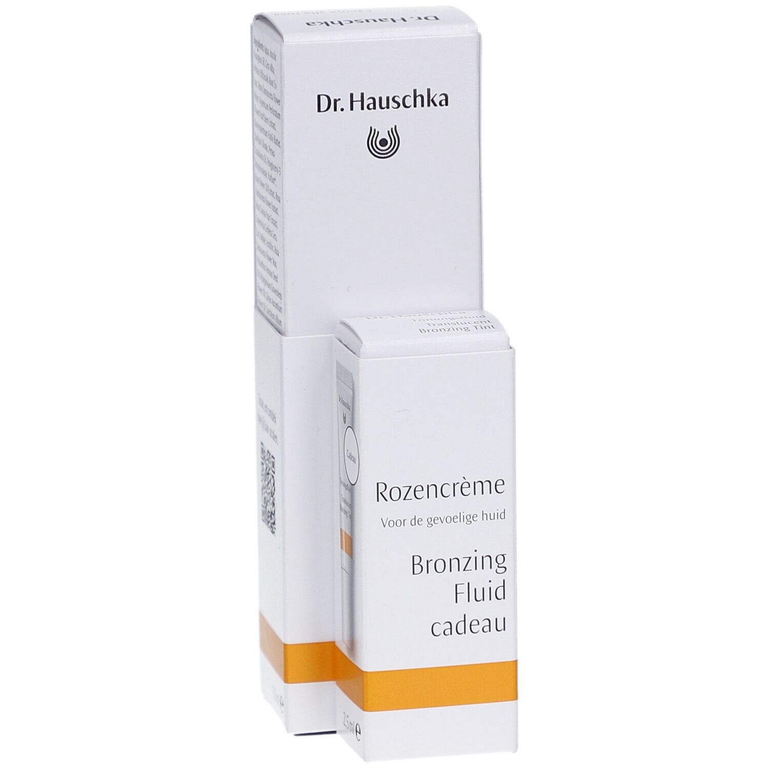Witte verpakking met Dr. Hauschka logo. Tekst: Rozencrème, Bronzing Fluid cadeau. Oranje streep.
