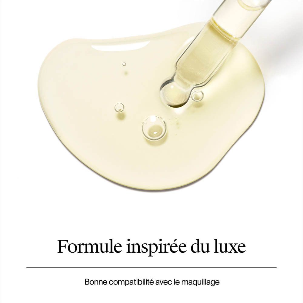 Goutte d'un liquide doré avec une pipette sur une surface blanche.