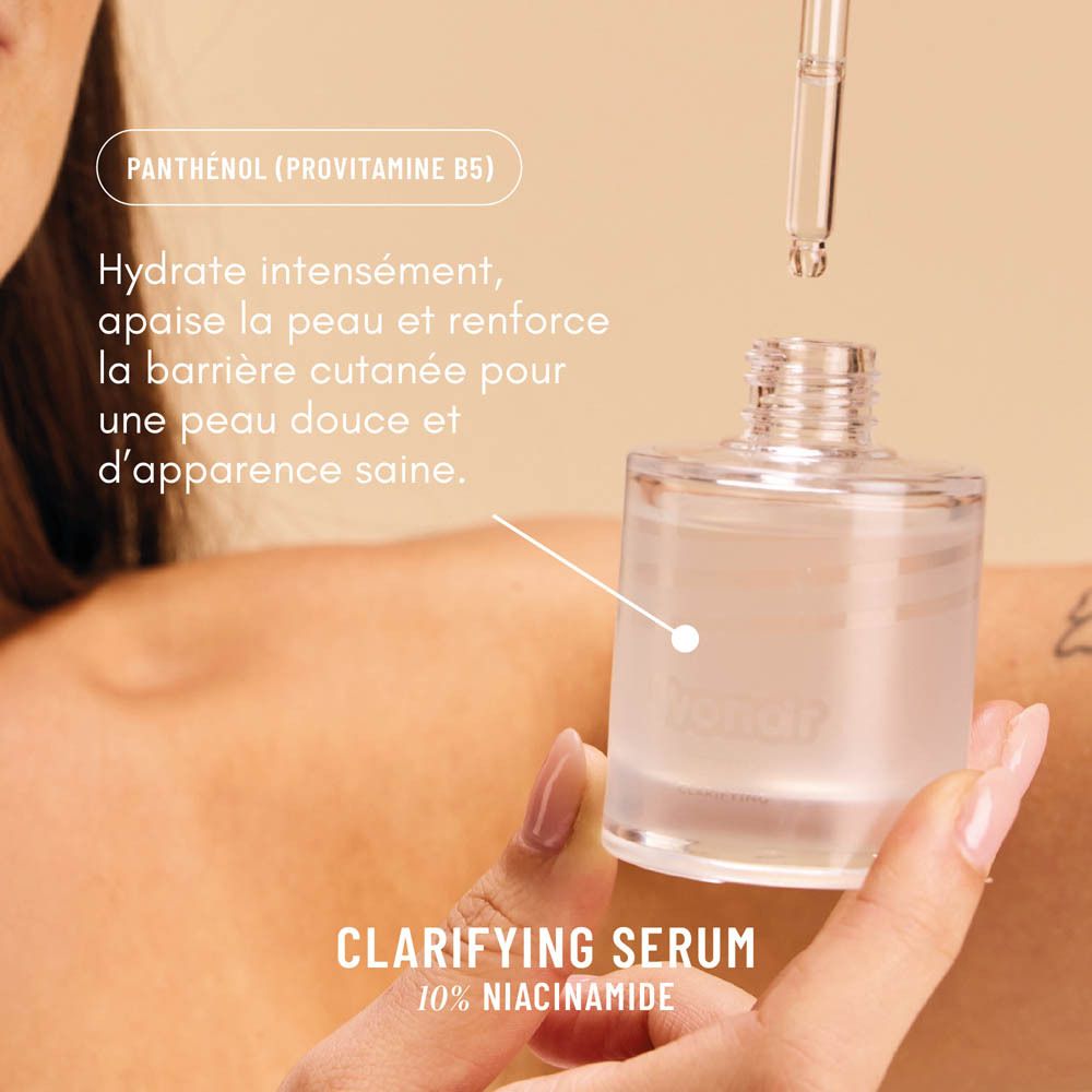 Mains tenant un flacon de sérum avec pipette. Libellé : Sérum Clarifiant, 10% Niacinamide. Texte : Hydrate, apaise.
