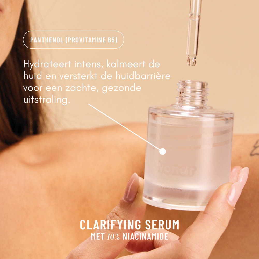 Handen houden serumfles met pipet. Label: Clarifying Serum, 10% Niacinamide. Tekst: Hydrateert, kalmeert.