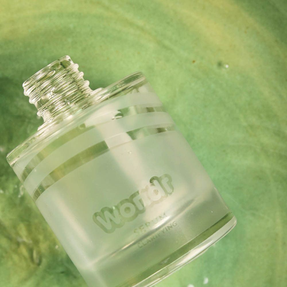Gros plan sur le flacon de sérum. Logo WONDR. Liquide vert en arrière-plan.