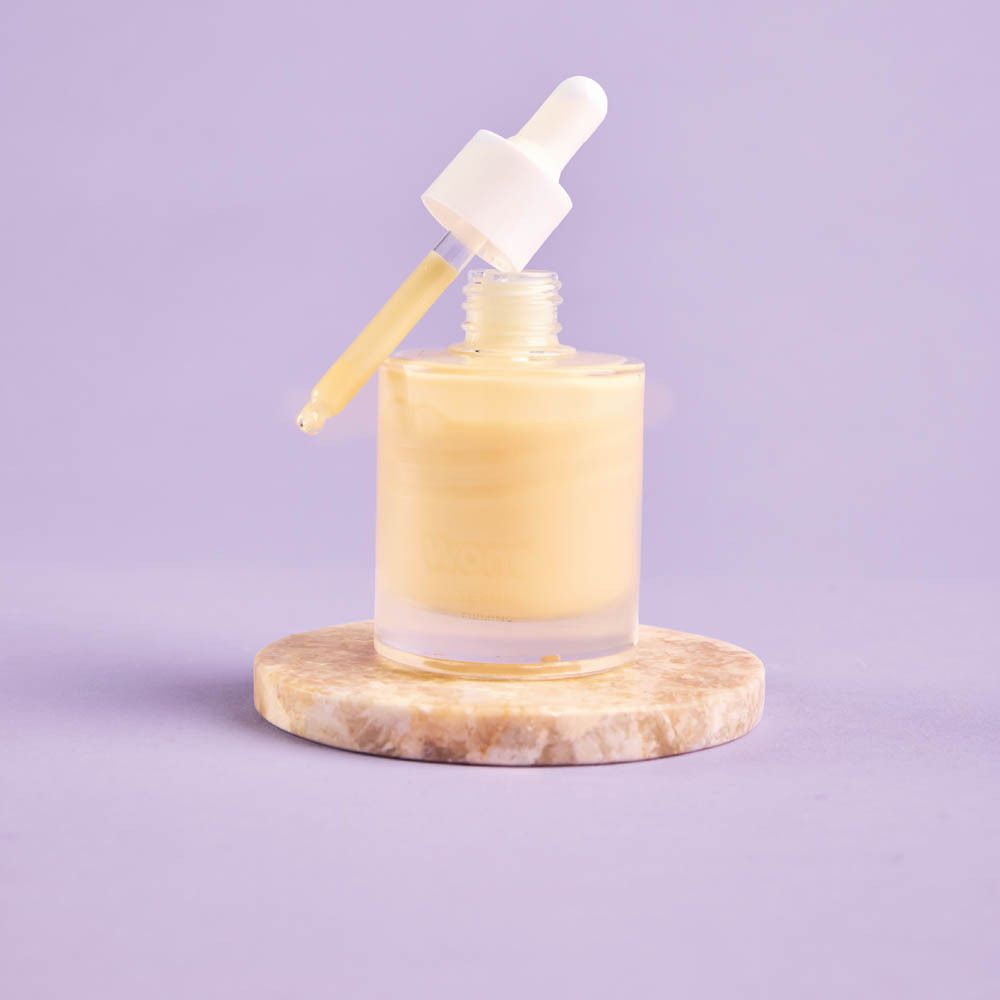 Flacon de sérum avec pipette. Liquide jaune. Fond violet.