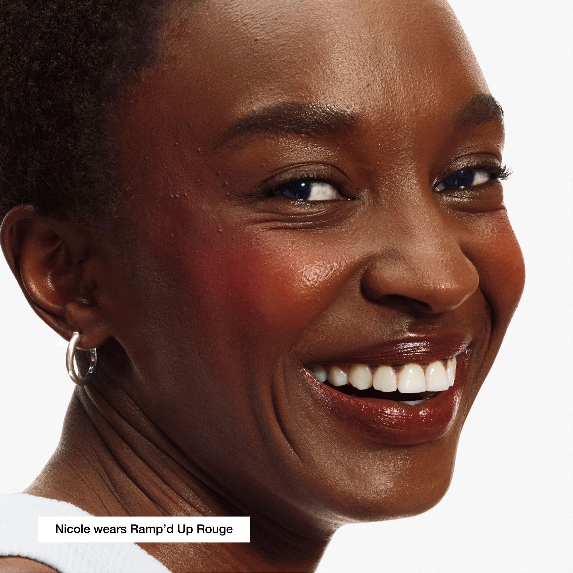 Vrouw met blush. Productnaam 'Ramp'd Up Rouge' zichtbaar. Merk niet genoemd.