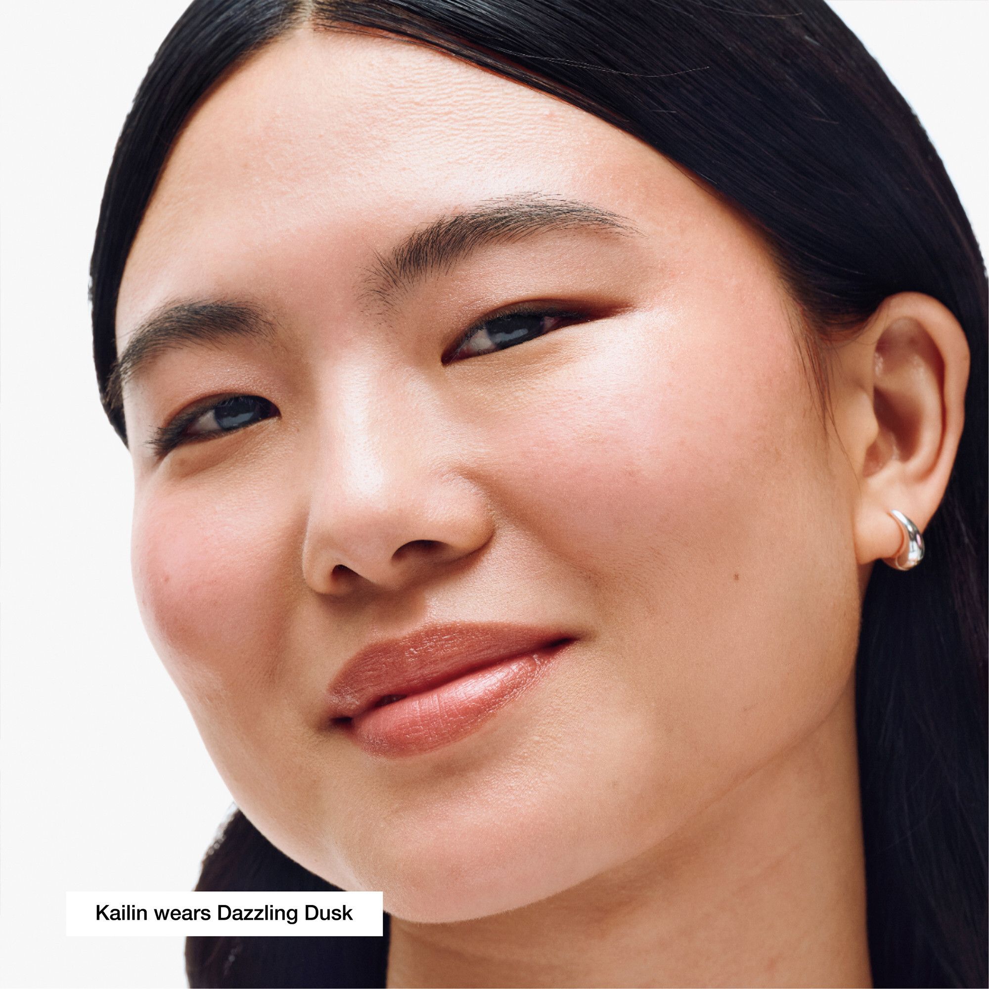 Visage avec highlighter. Texte: 'Kailin wears Dazzling Dusk'.