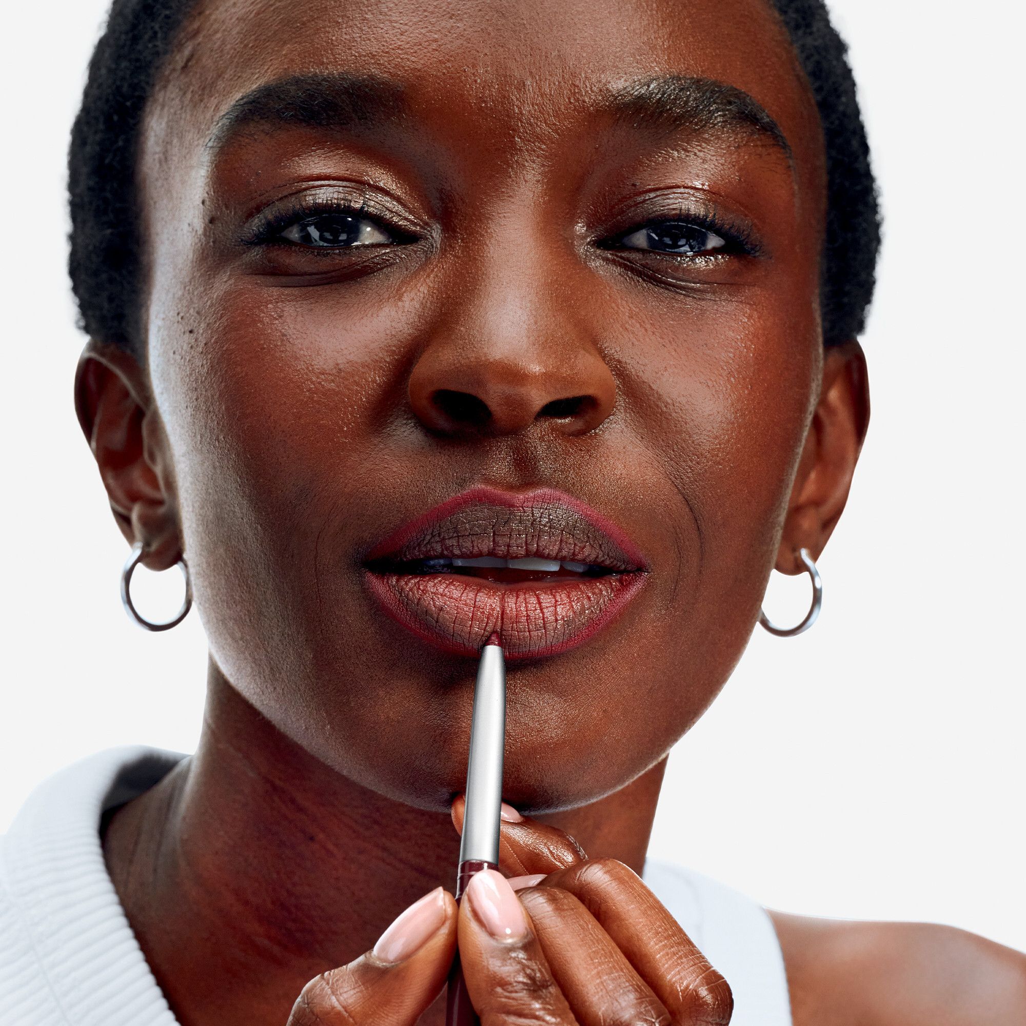 Gros plan d'une femme qui se dessine les lèvres avec un crayon contour. Stylo argenté.