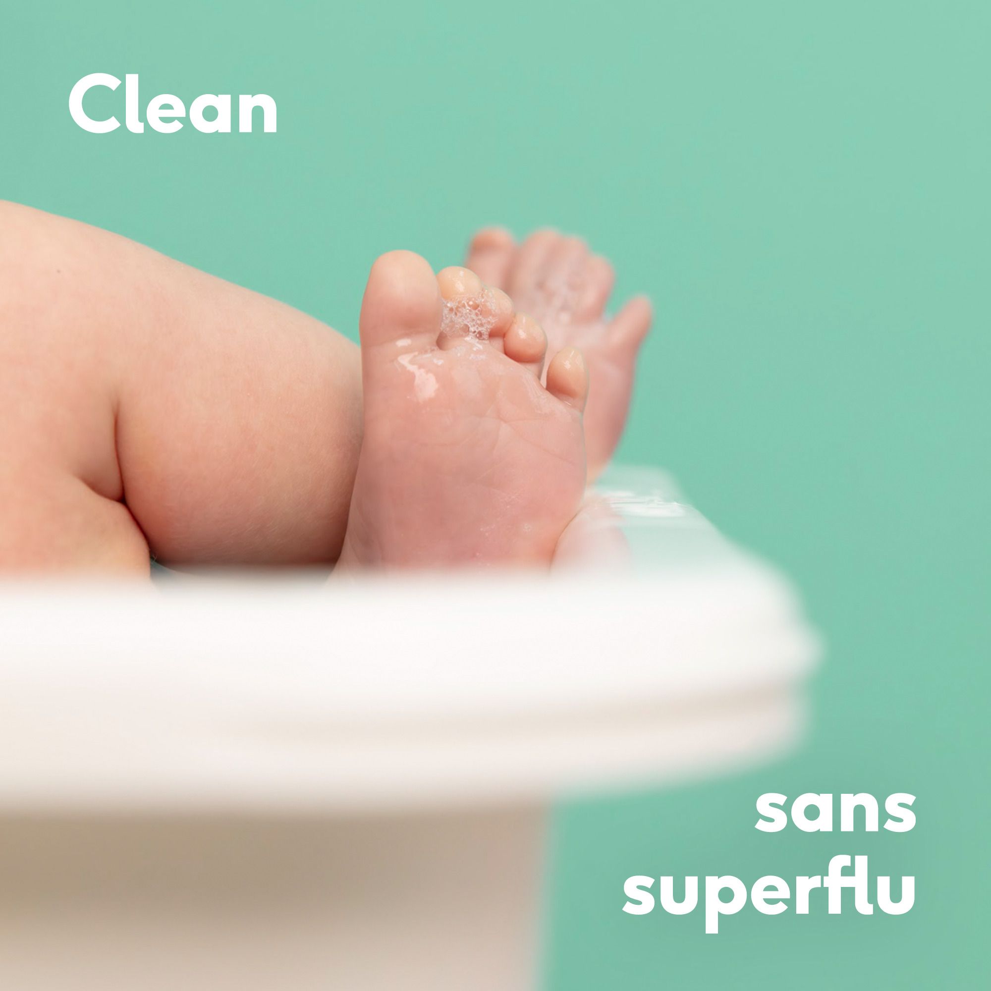 Gros plan sur les pieds d'un bébé dans une baignoire. Texte : Propre, sans superflu. Fond turquoise.