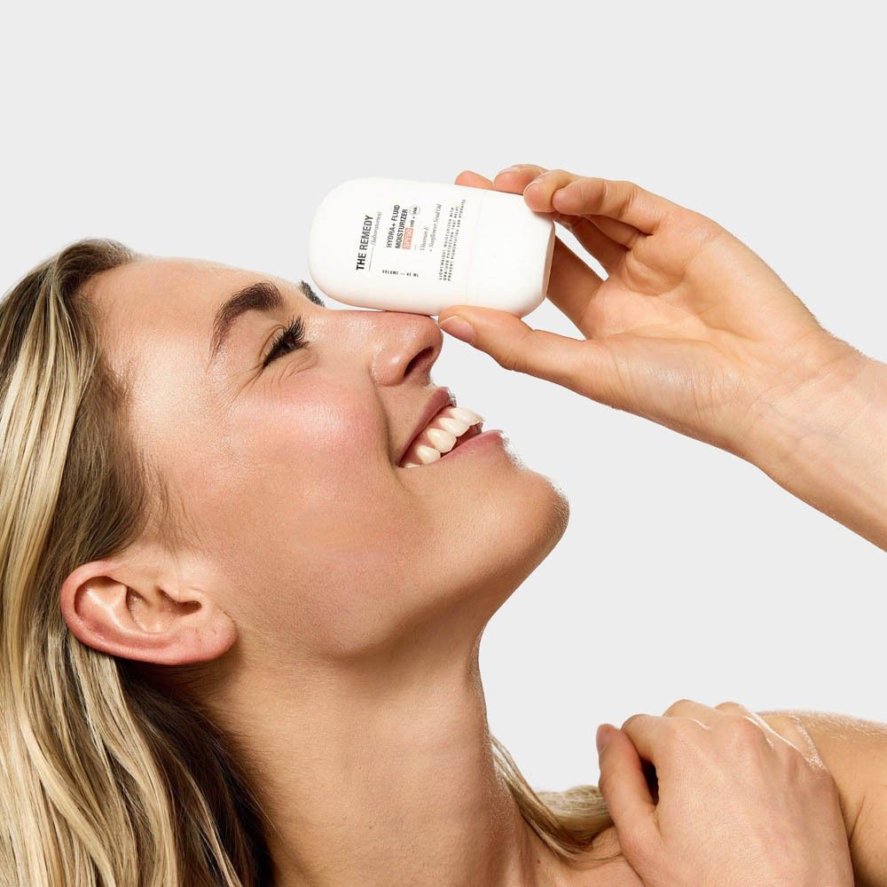 Hydra+ Fluid Moisturizer SPF50, flacon posé sur une surface de peau.