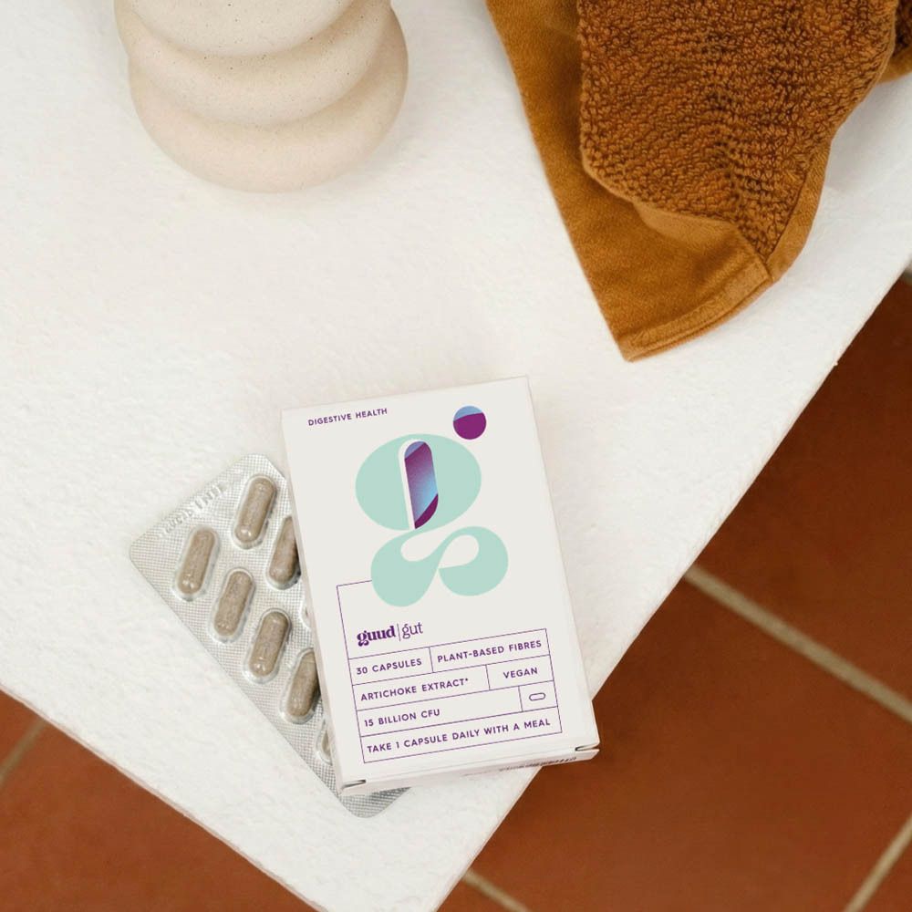 Productverpakking en blisterverpakking op wit oppervlak. Opschrift: Guud Gut, 30 capsules, plantaardige vezels, artisjokextract, vegan.