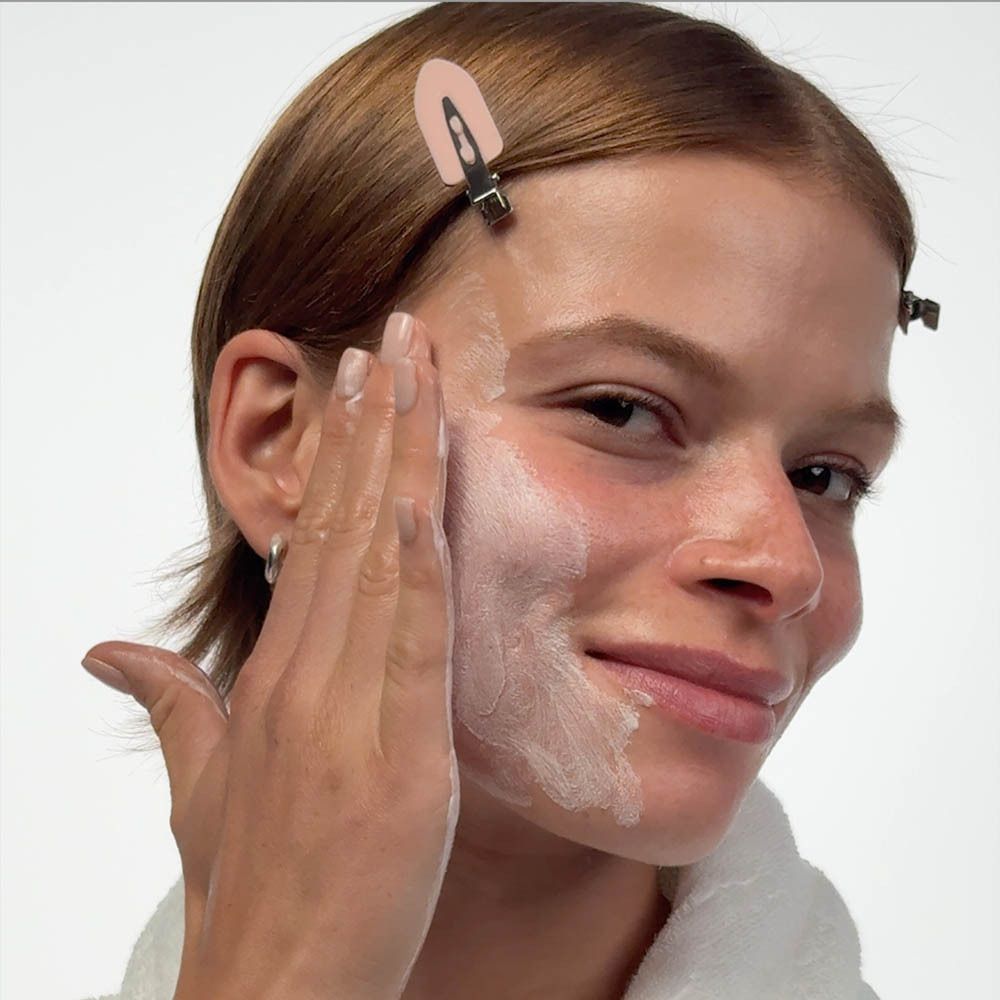 Close-up van een lichtroze textuur met bubbels en lagen, die reiniging en peeling symboliseren.