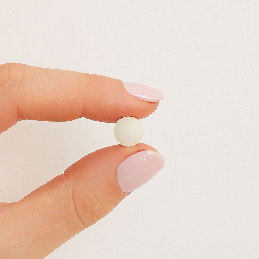 Een enkele, ronde, witte tablet in een hand.