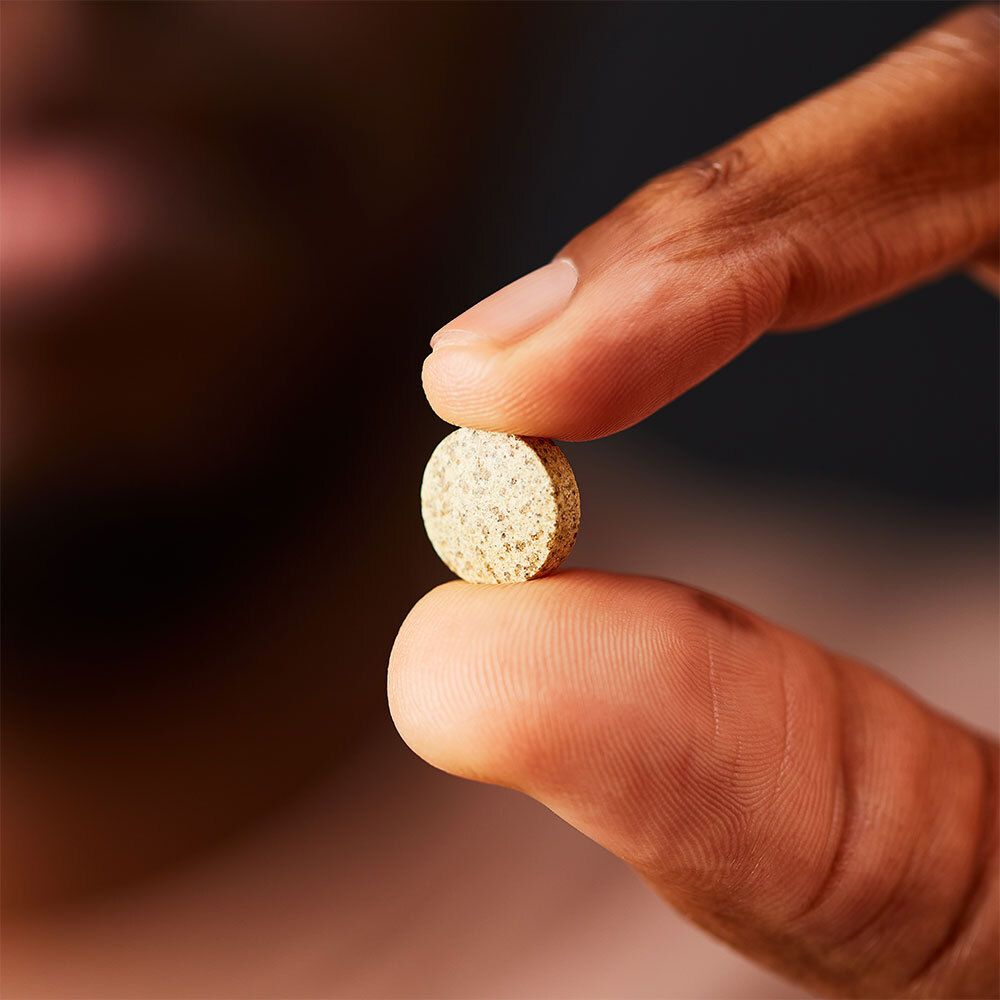 Hand houdt tablet vast. Tablet tussen duim en wijsvinger.