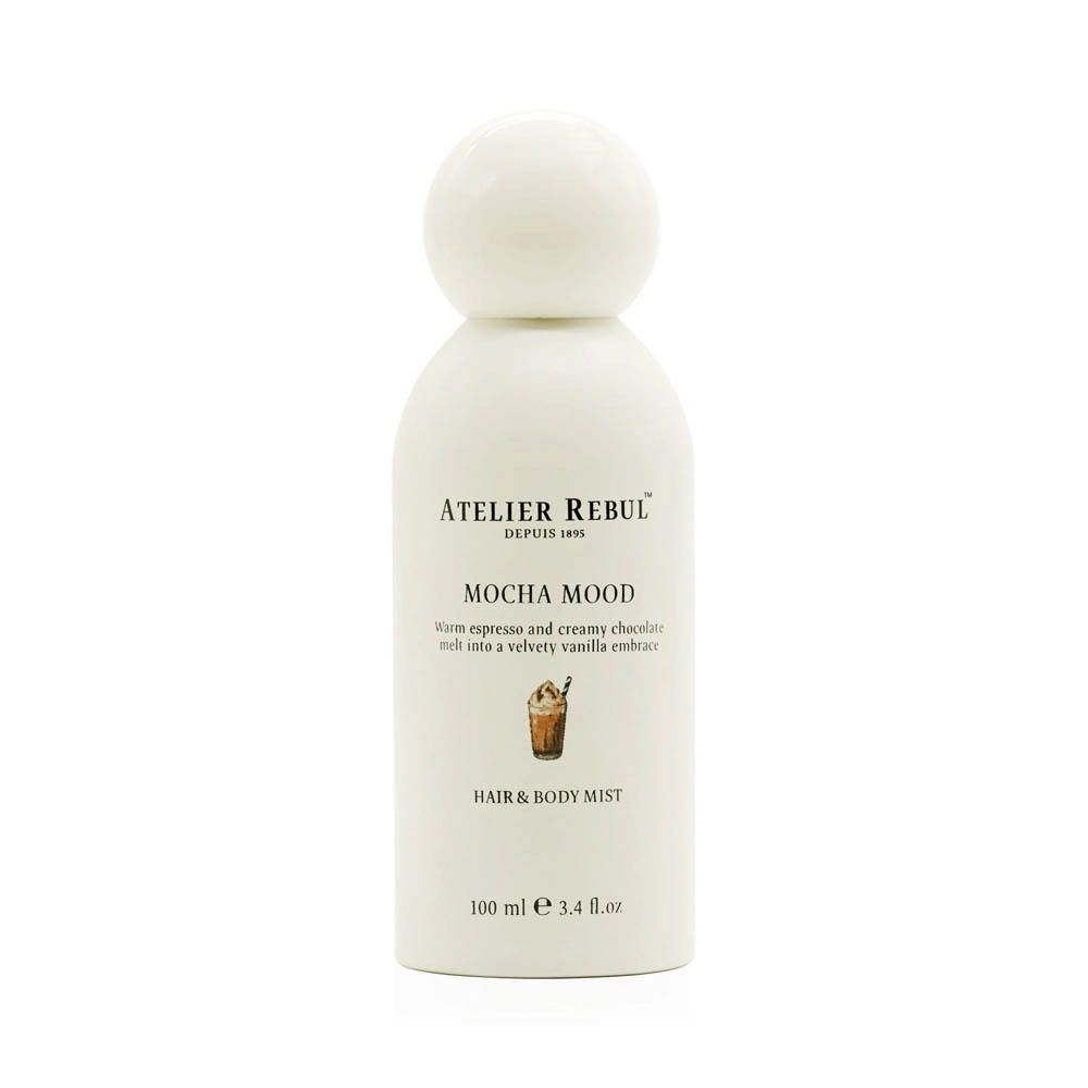 Witte fles met ronde dop. Opschrift: ATELIER REBUL, MOCHA MOOD, HAIR & BODY MIST. Onderaan: 100 ml e 3.4 fl.oz.
