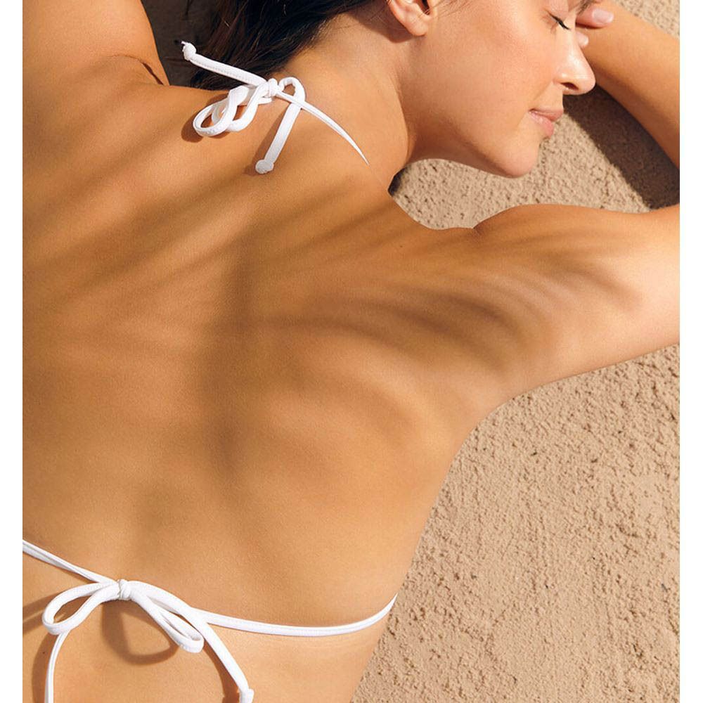 Vrouw ligt op haar buik. Zonnebrand op rug. Witte bikini.