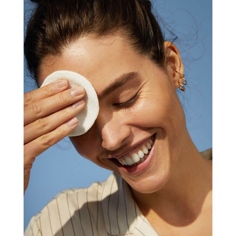 Een vrouw reinigt haar oog met een wattenschijfje en NIVEA Rose Care micellair rozenwater.