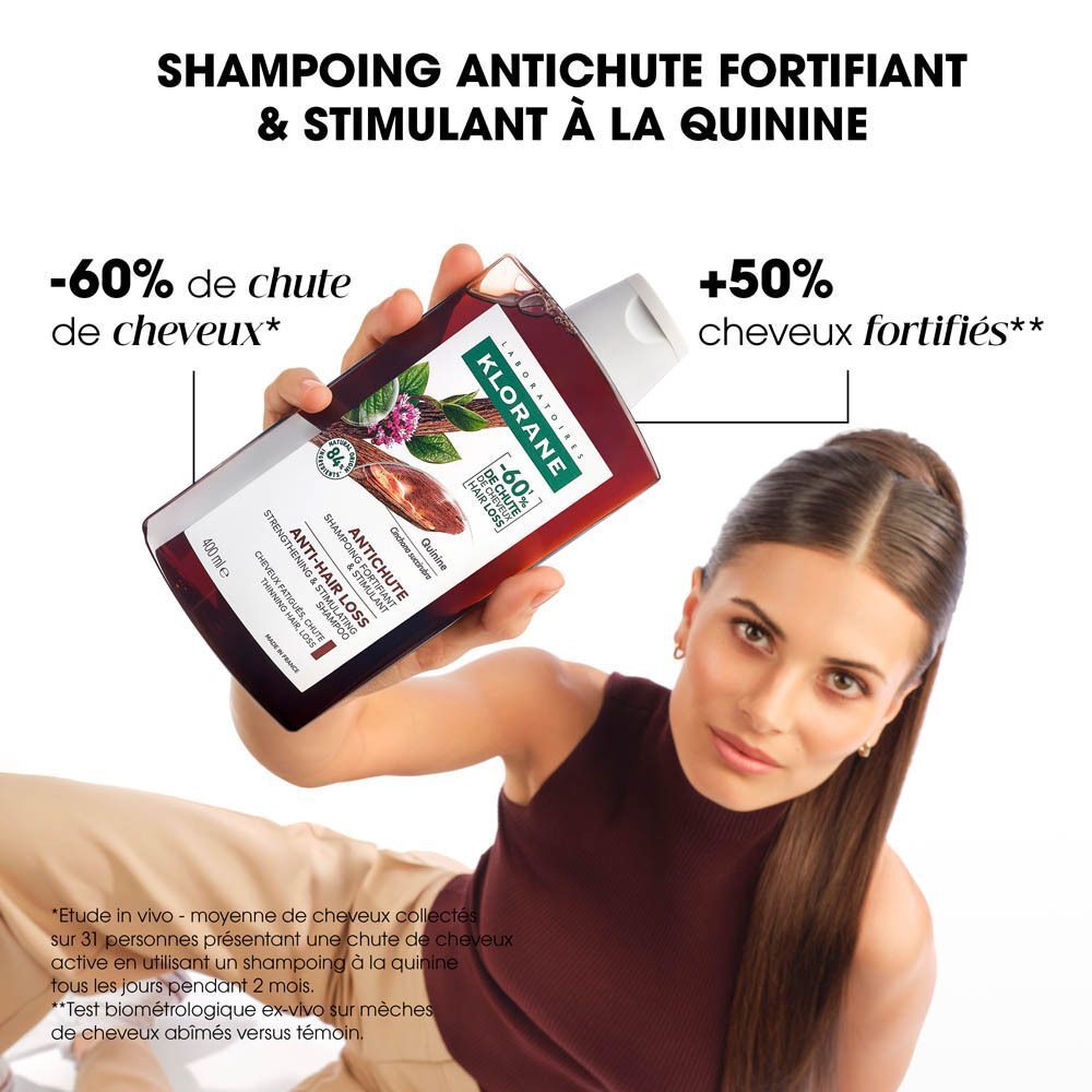 Bouteille de shampoing Klorane à la quinine anti-chute, 400ml, tenue par une femme.