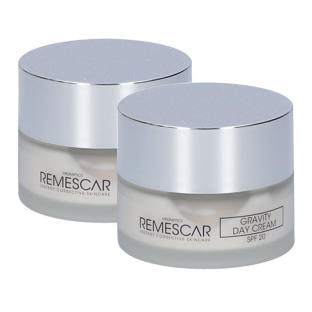 Twee crèmepotten met zilveren deksels. Opschrift: REMESCAR, GRAVITY DAY CREAM SPF 20. Glazen potten met romige substantie.