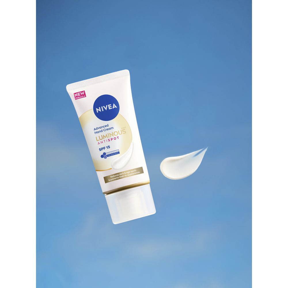 Een hand houdt een NIVEA® CELLULAR LUMINOUS630® handcrème tube vast tegen een blauwe hemel.