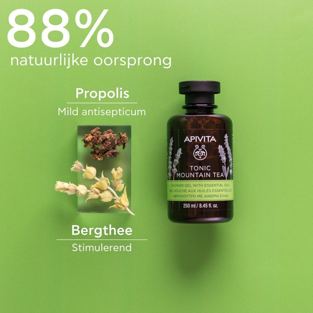 Fles douchegel naast kruiden en propolis. Opschrift: Apivita, Tonic Mountain Tea, 250 ml. Tekst: 88% natuurlijke oorsprong.