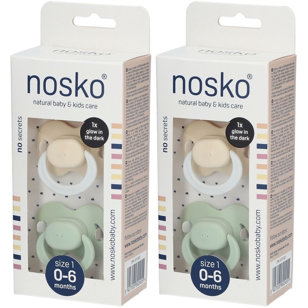 Deux sucettes dans un emballage. Marque : nosko. Sucettes beiges et vertes. Taille 1, 0-6 mois. Brille dans le noir.