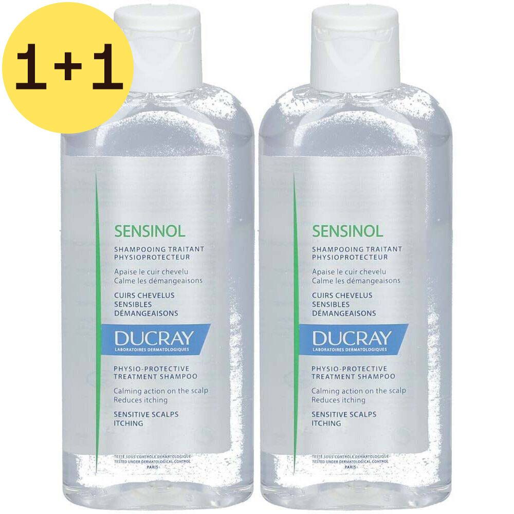 Twee transparante shampoo flessen met witte dop. Op elke fles staat "SENSINOL" en "DUCRAY". Gele sticker met "1+1".