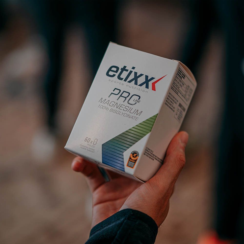 Une main tient une boîte blanche avec l'inscription etixx PRO Magnesium 100% Bisglycinate. Inscription: 60x.