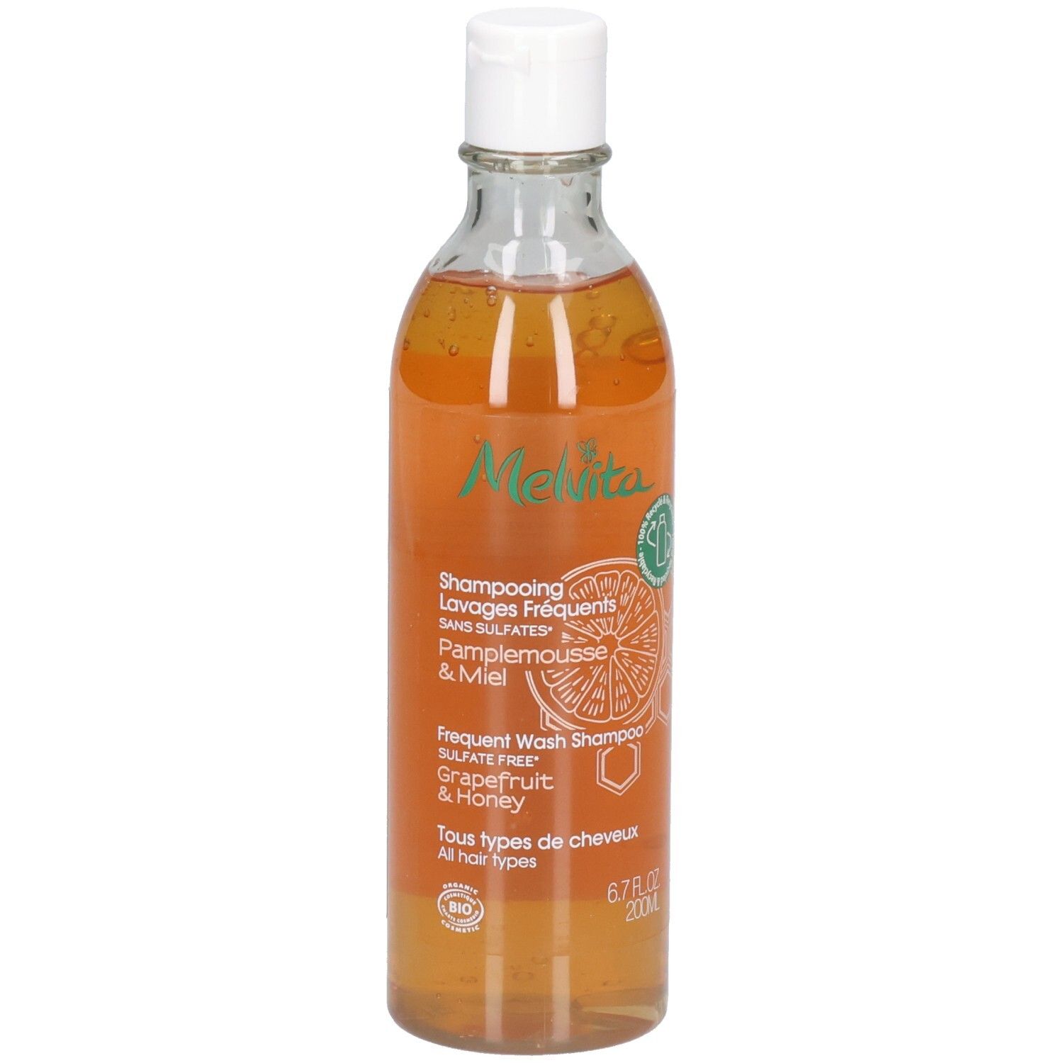 Melvita Shampoo: Grapefruit & Honing, 200ml. Transparante fles met witte dop. Oranje vloeistof.